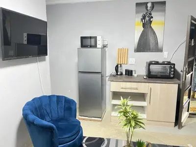 a living room with a blue chair and a television at samama guesthouse in Groblersdal