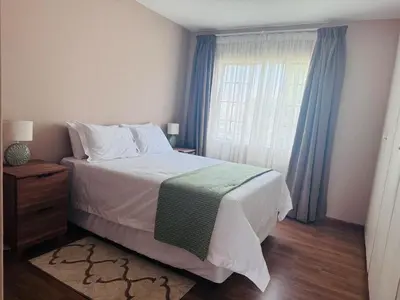 a bedroom with a bed and a window with blue curtains at Lovely Home away from Home in Centurion