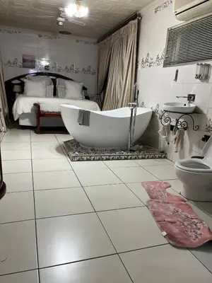 a bathroom with a large tub and a bed at Berry Home 4U in Pretoria