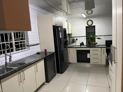 a large kitchen with black appliances and white tiles at Berry Home 4U in Pretoria