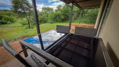 a screened in porch with a table and chairs and a pool at Casa de la Presa 5 in Polokwane