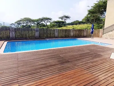 a swimming pool with a wooden deck next to a fence at Elephant Villa in Nelspruit