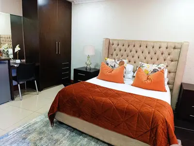 a bedroom with a large bed with orange pillows at Elephant Villa in Nelspruit