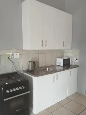 a kitchen with white cabinets and a sink and a stove at Entire rental unit in Pretoria