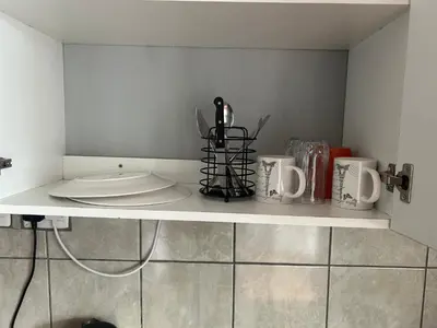 a shelf with cups and utensils on it at Entire rental unit in Pretoria
