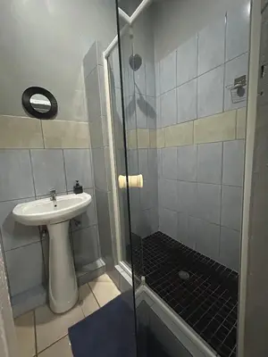 a bathroom with a sink and a glass shower at Entire rental unit in Pretoria