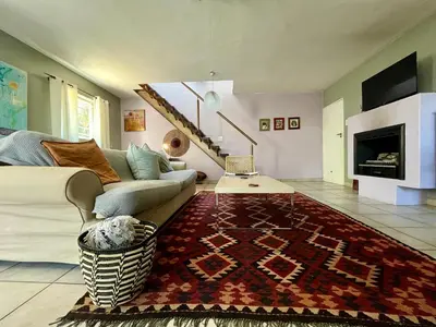 a living room with a couch and a rug at Tranquility in the Trees Loft Style Apartment in Pretoria
