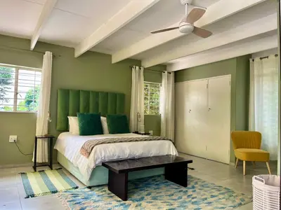 a bedroom with green walls and a bed with a table at Tranquility in the Trees Loft Style Apartment in Pretoria