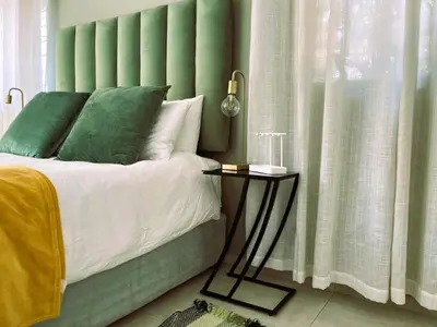 a bed with a green headboard and a side table at Tranquility in the Trees Loft Style Apartment in Pretoria