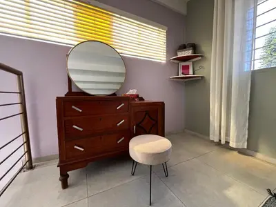 a dressing room with a mirror on a dresser and a stool at Tranquility in the Trees Loft Style Apartment in Pretoria