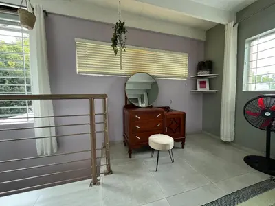 a room with a mirror and a dresser and a chair at Tranquility in the Trees Loft Style Apartment in Pretoria