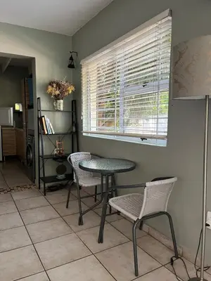 a dining room with a table and chairs and a window at Tranquility in the Trees Loft Style Apartment in Pretoria