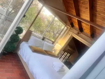 a bed in a room with a large window at Executive loft at Brooklyn in Pretoria