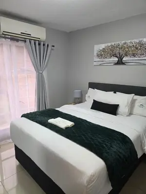 a bedroom with a large bed with a green blanket at Ikar's Haven in Centurion