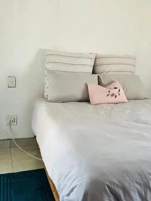 a white bed with a pink pillow on it at The Ripanga Nest in Nelspruit