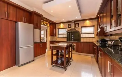 a large kitchen with wooden cabinets and a white refrigerator at Dream Retreat Pecanwood Golf Estate in Hartbeespoort