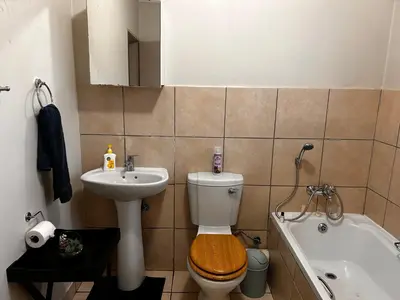 a bathroom with a toilet and a sink and a bath tub at Castle in the Capital City 3-Beds in Pretoria