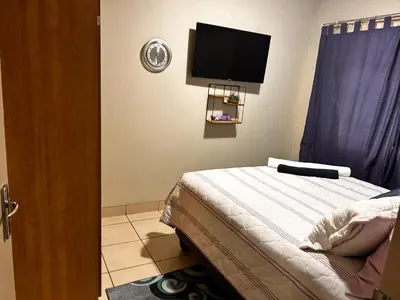 a bedroom with a bed and a flat screen tv at Castle in the Capital City 3-Beds in Pretoria