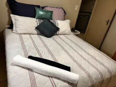 a bed with pillows on it with a white comforter at Castle in the Capital City 3-Beds in Pretoria
