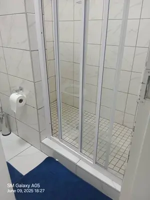 a shower in a bathroom with a roll of toilet paper at Emlomo logde in Ermelo