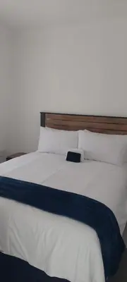 a large white bed with a wooden head board at Emlomo logde in Ermelo
