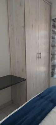 a bedroom with a bed and a wooden cabinet at Emlomo logde in Ermelo