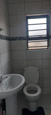 a bathroom with a toilet and a sink and a window at Emlomo logde in Ermelo