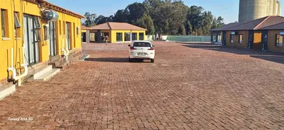 a white car parked on a brick road next to buildings at Emlomo logde in Ermelo