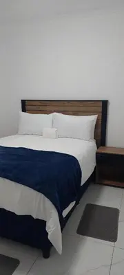a large bed with a blue blanket and white pillows at Emlomo logde in Ermelo