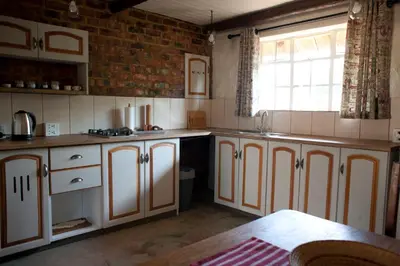 a kitchen with white cabinets and a window at Stone Cottage in Tierpoort