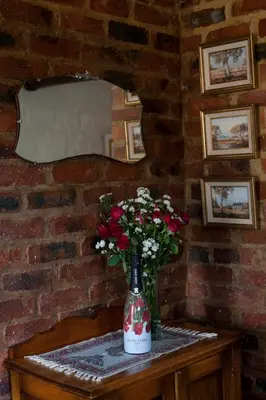 a vase of flowers on a table with a brick wall at Stone Cottage in Tierpoort