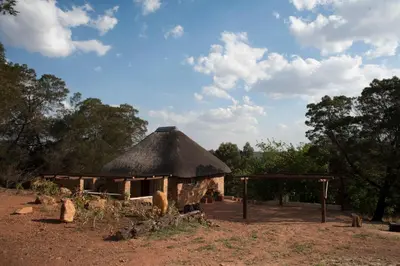 a hut with a thatched roof in a field at Stone Cottage in Tierpoort