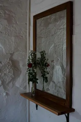 a mirror with two vases of flowers on a shelf at Stone Cottage in Tierpoort