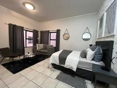 a bedroom with a bed and a couch and a chair at The Lagoon in Pretoria