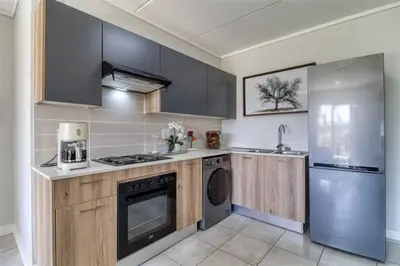 a kitchen with wooden cabinets and a washer and dryer at The Lagoon in Pretoria