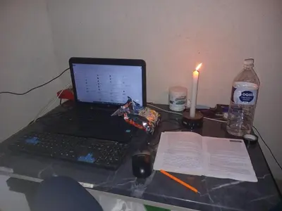 a desk with a laptop computer and a candle and a book at Charming 3 - Bedroom Home in Mangweni