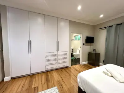 a bedroom with white cabinets and a bed at Vinorisa Spa & Lodge in Pretoria