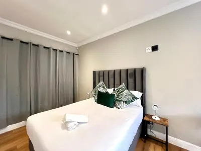 a bedroom with a bed with white sheets and green pillows at Vinorisa Spa & Lodge in Pretoria
