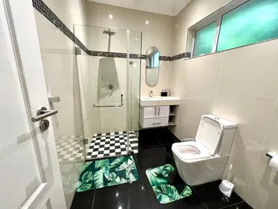 a bathroom with a toilet and a glass shower at Vinorisa Spa & Lodge in Pretoria