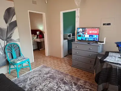a living room with a television on a dresser and a bedroom at Mountain View Cottage in Barberton