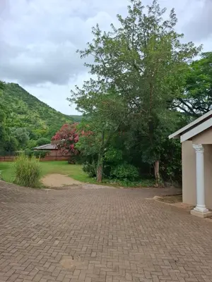 a brick driveway with a tree and a house at Mountain View Cottage in Barberton