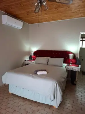 a bedroom with a large bed with a red headboard at Mountain View Cottage in Barberton