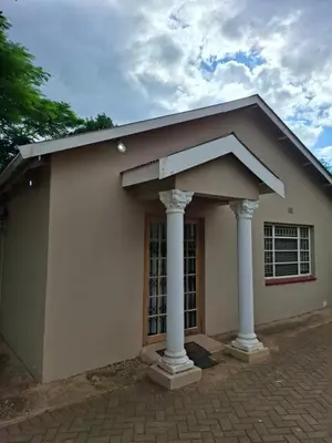 a small white house with two pillars at Mountain View Cottage in Barberton