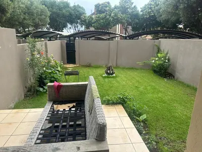 a backyard with a bench in the grass at Kwa Ndosi in Polokwane