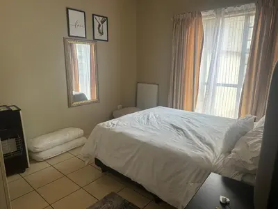a bedroom with a white bed and a window at Kwa Ndosi in Polokwane
