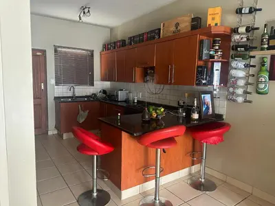 a kitchen with red bar stools at a counter at Kwa Ndosi in Polokwane
