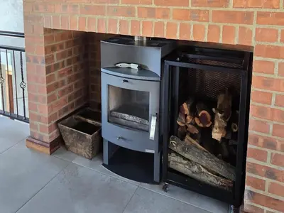 a brick fireplace with a stove in it at Ironwood Manor in Dullstroom
