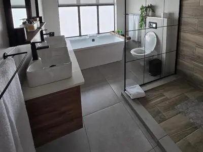 a bathroom with a tub and a sink and a toilet at Ironwood Manor in Dullstroom