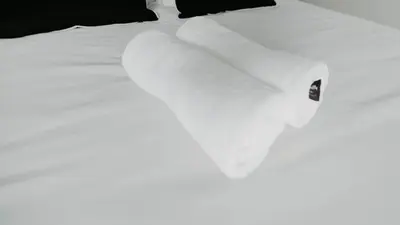 a close up of a bed with white sheets and pillows at The Blyde Crystal Lagoon Apartment in Pretoria