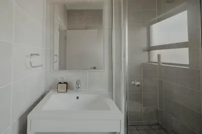 a white bathroom with a sink and a shower at The Blyde Crystal Lagoon Apartment in Pretoria